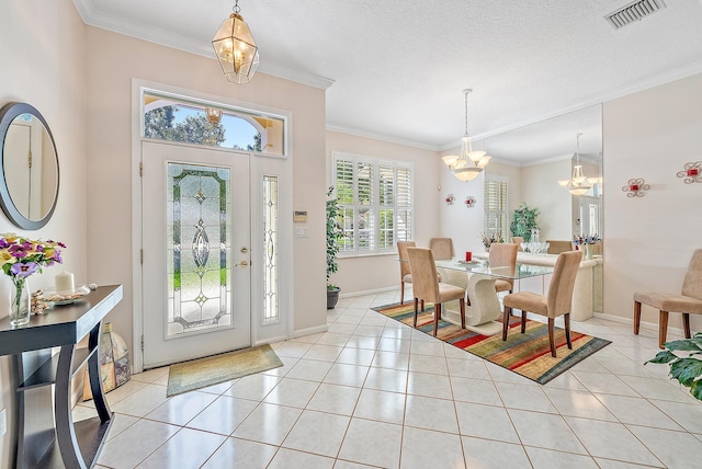 foyer entrance featuring a textured ceiling, crown molding, a chandelier, and light tile patterned floors