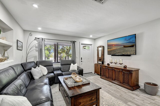 living room with light hardwood / wood-style floors and a textured ceiling