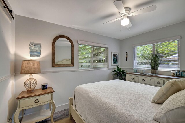 bedroom with ceiling fan, dark hardwood / wood-style floors, and multiple windows