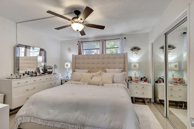 bedroom featuring a textured ceiling, ceiling fan, a closet, and light wood-type flooring