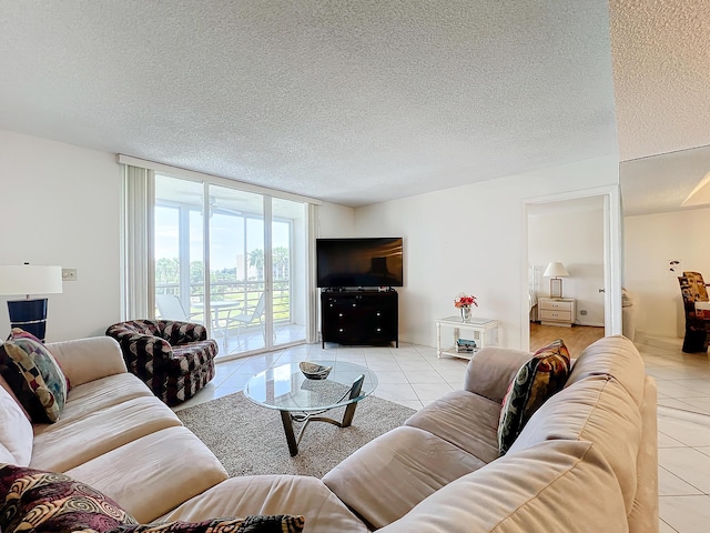 living room featuring light tile patterned floors, a textured ceiling, and a wall of windows