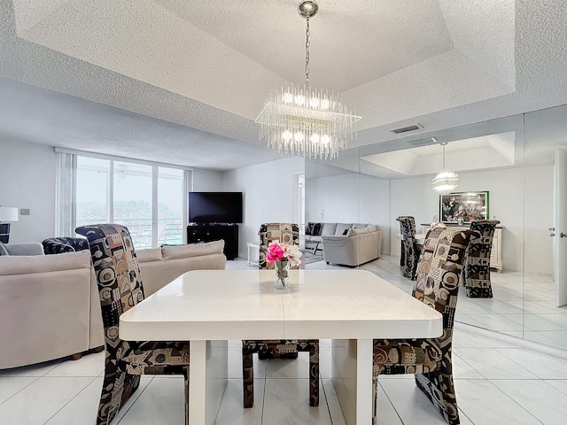 tiled dining area featuring a tray ceiling, a chandelier, and a textured ceiling