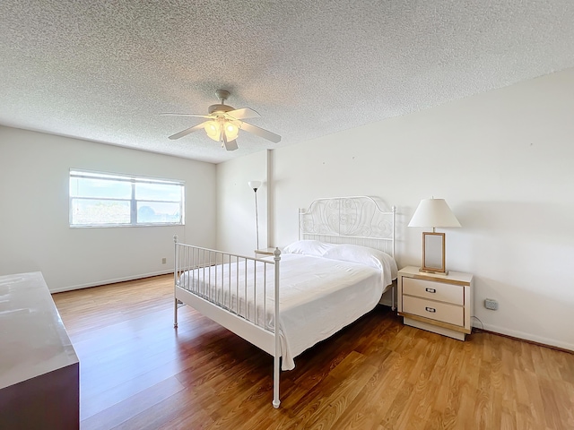 bedroom with ceiling fan, a textured ceiling, baseboards, and wood finished floors