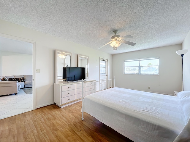 bedroom with light wood finished floors, baseboards, a ceiling fan, and a textured ceiling