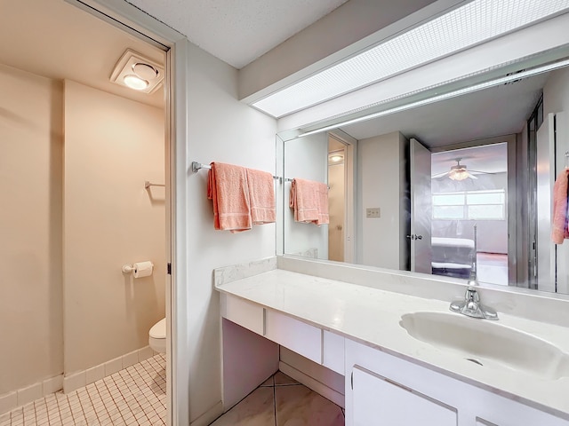 bathroom with toilet, tile patterned floors, baseboards, and vanity