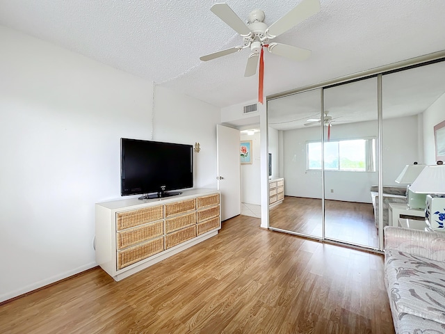 bedroom featuring light wood finished floors, visible vents, ceiling fan, a textured ceiling, and a closet