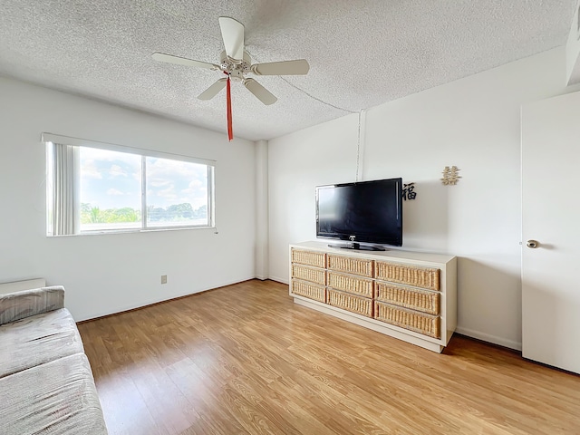 unfurnished living room with ceiling fan, a textured ceiling, baseboards, and wood finished floors