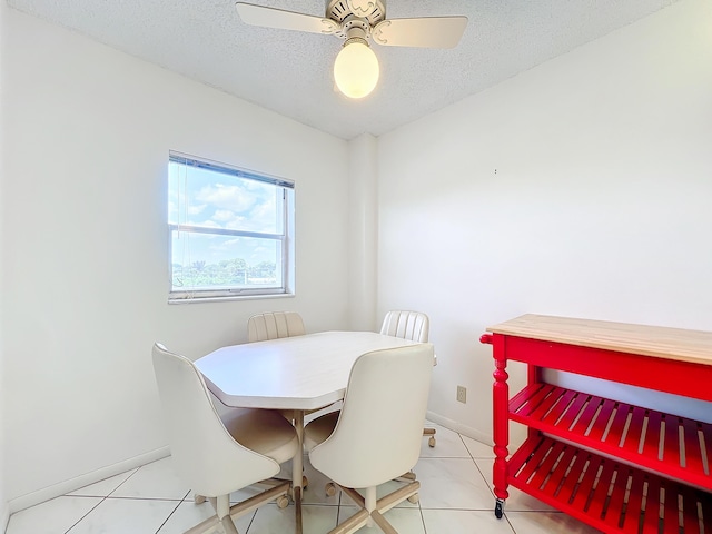 dining room with light tile patterned floors, ceiling fan, baseboards, and a textured ceiling