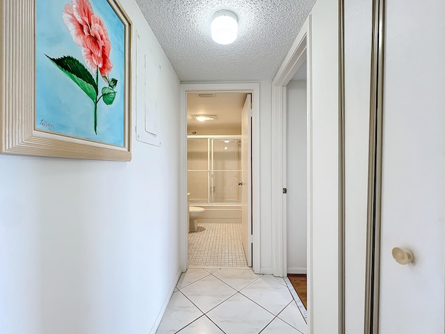 hallway featuring light tile patterned floors and a textured ceiling