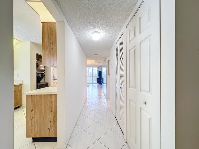 corridor featuring a textured ceiling and light tile patterned flooring