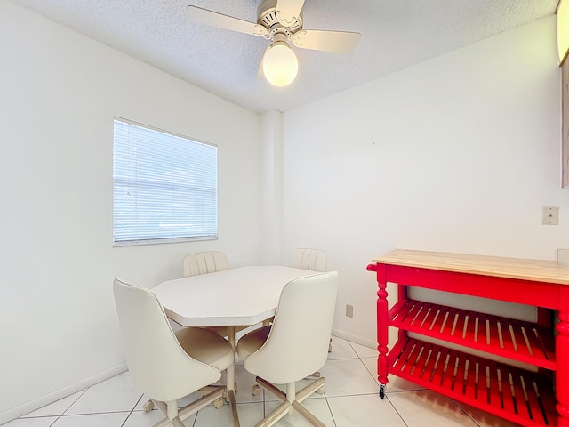 dining room featuring light tile patterned floors, ceiling fan, a textured ceiling, and baseboards