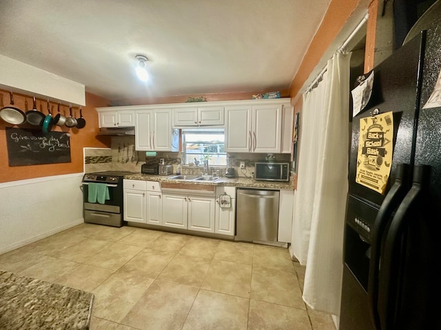 kitchen with appliances with stainless steel finishes, white cabinetry, light tile patterned floors, and sink