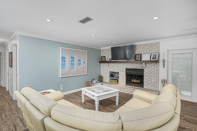 living room featuring ornamental molding, dark hardwood / wood-style floors, a brick fireplace, and a textured ceiling