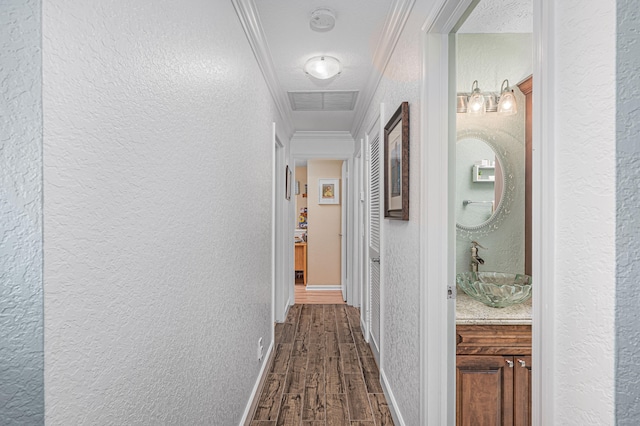 corridor featuring ornamental molding, a textured ceiling, sink, and dark hardwood / wood-style floors