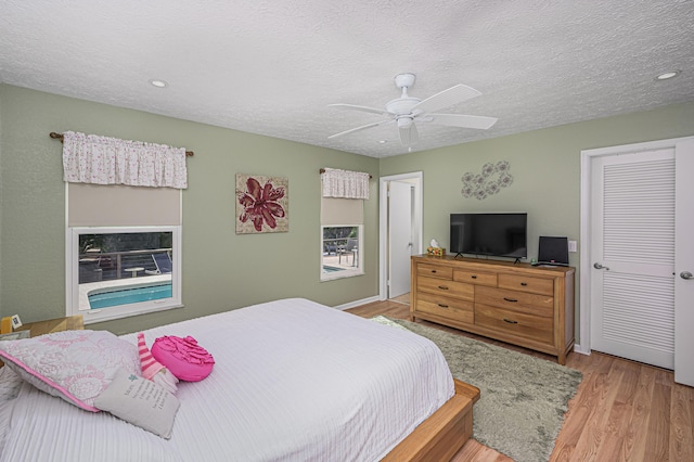 bedroom featuring ceiling fan, a textured ceiling, and light hardwood / wood-style flooring