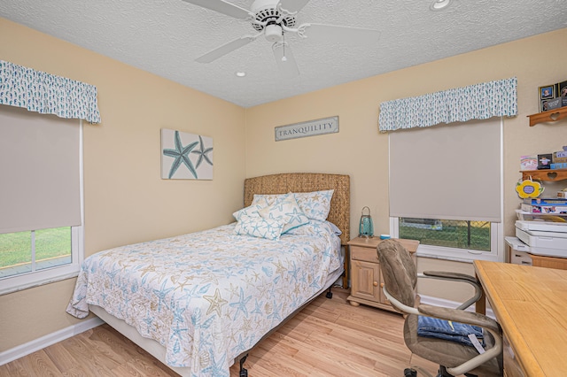 bedroom with light wood-type flooring, ceiling fan, and a textured ceiling