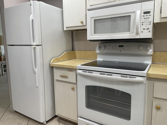 kitchen with white appliances, tasteful backsplash, light countertops, and light tile patterned flooring