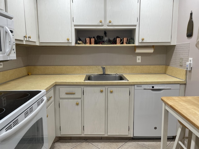 kitchen with light tile patterned floors, light countertops, decorative backsplash, a sink, and white appliances