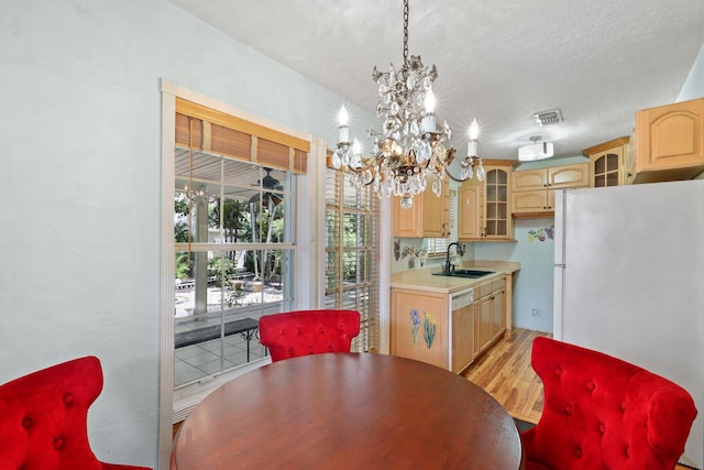 dining room with a textured ceiling, light wood finished floors, a chandelier, and visible vents