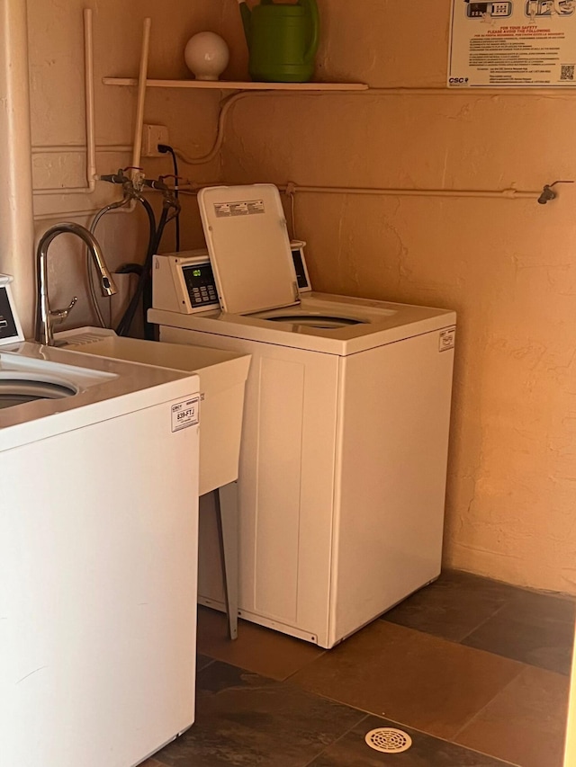 clothes washing area with washer and dryer and dark tile patterned floors