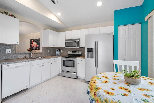 kitchen featuring appliances with stainless steel finishes, white cabinetry, tasteful backsplash, sink, and light tile patterned floors