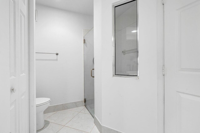 bathroom featuring toilet, an enclosed shower, and tile patterned flooring