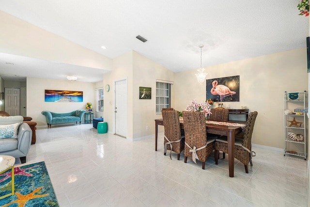 tiled dining room featuring an inviting chandelier and lofted ceiling