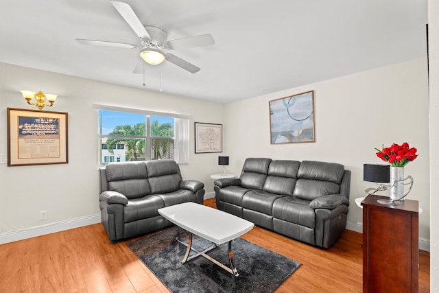 living area featuring a ceiling fan, baseboards, and wood finished floors