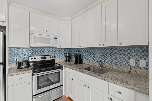 kitchen featuring appliances with stainless steel finishes, white cabinets, a sink, and decorative backsplash