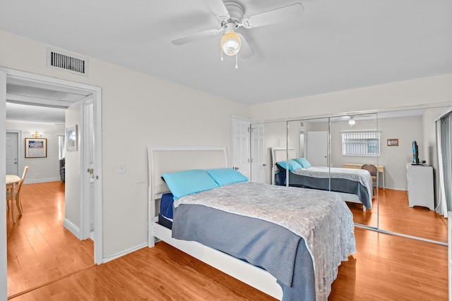 bedroom featuring a closet, visible vents, ceiling fan, wood finished floors, and baseboards