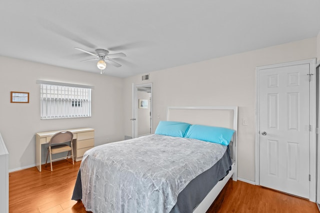 bedroom with baseboards, visible vents, ceiling fan, and wood finished floors