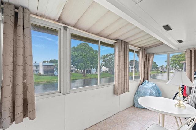 sunroom featuring beamed ceiling and a water view