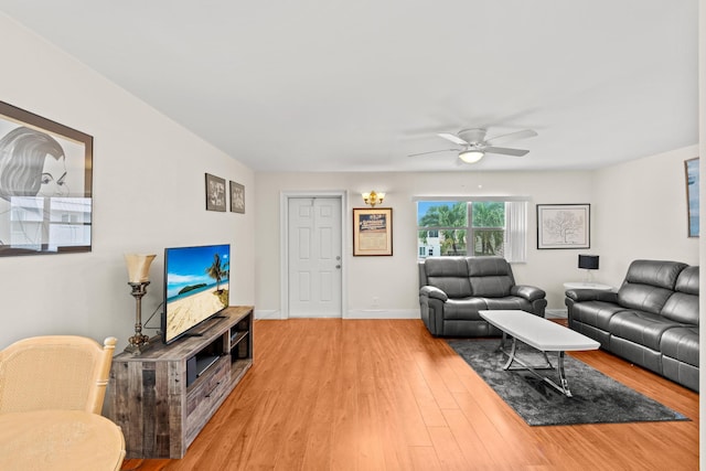 living area with a ceiling fan, baseboards, and wood finished floors