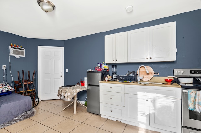 kitchen with white cabinetry, appliances with stainless steel finishes, a wall mounted air conditioner, and light tile patterned flooring