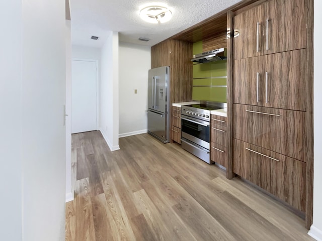 kitchen featuring a textured ceiling, appliances with stainless steel finishes, and light hardwood / wood-style flooring