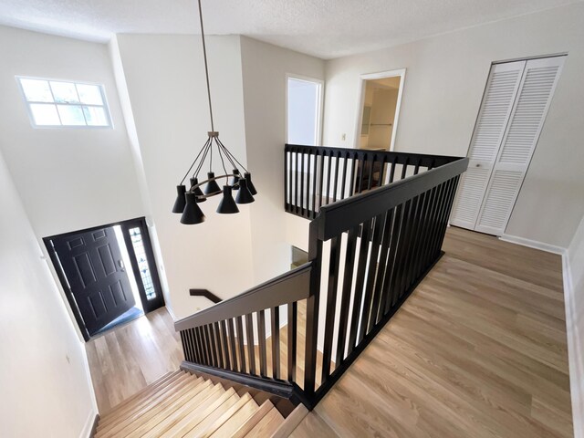 stairs featuring hardwood / wood-style floors and an inviting chandelier