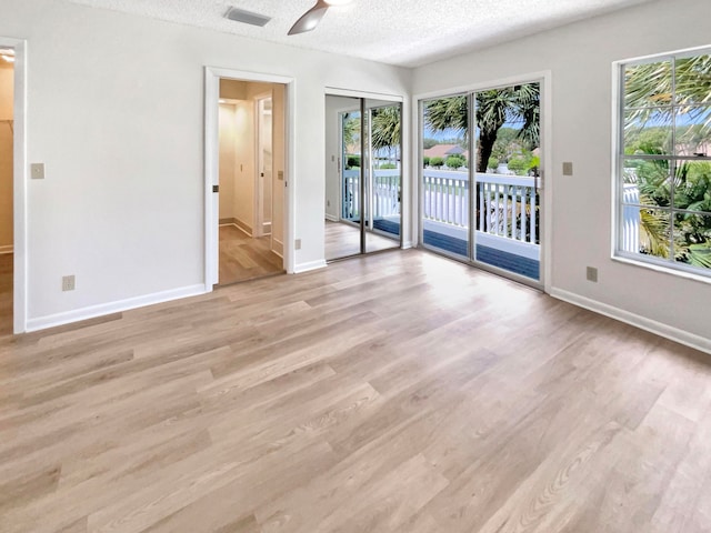 unfurnished room with a textured ceiling, light hardwood / wood-style floors, and a healthy amount of sunlight