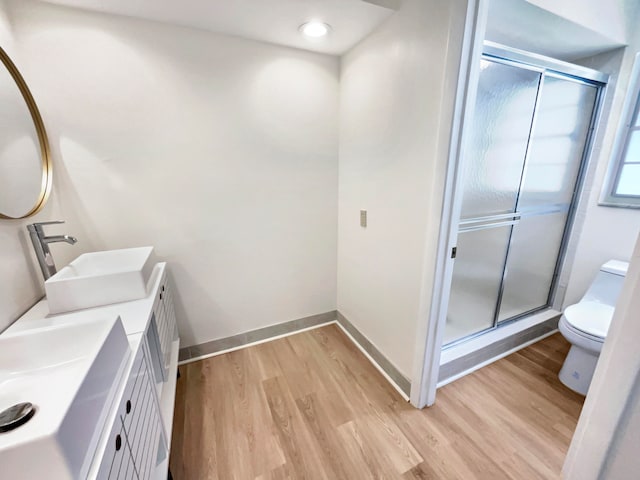 bathroom featuring an enclosed shower, toilet, vanity, and wood-type flooring