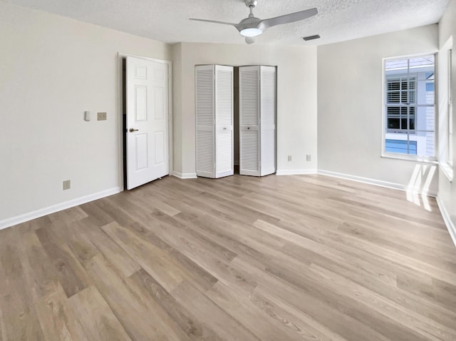 unfurnished bedroom featuring ceiling fan, light hardwood / wood-style flooring, and a textured ceiling