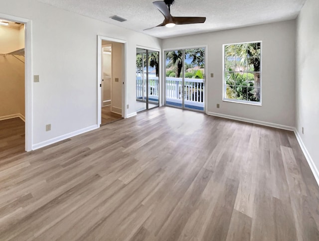 interior space with a textured ceiling, light wood-type flooring, and ceiling fan