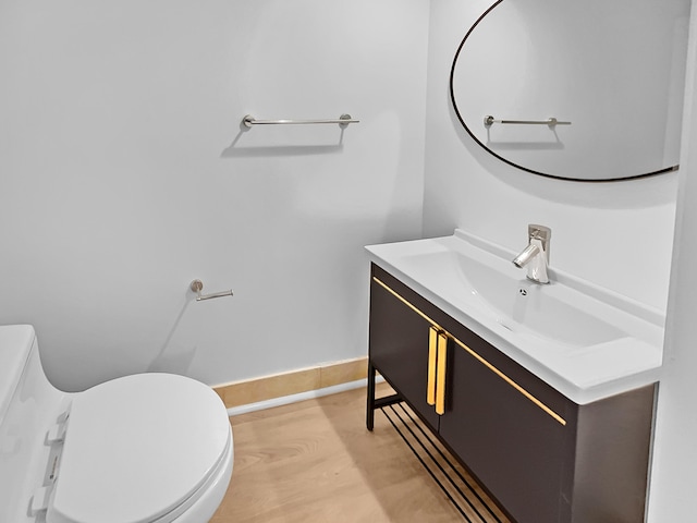 bathroom with hardwood / wood-style flooring, toilet, and vanity