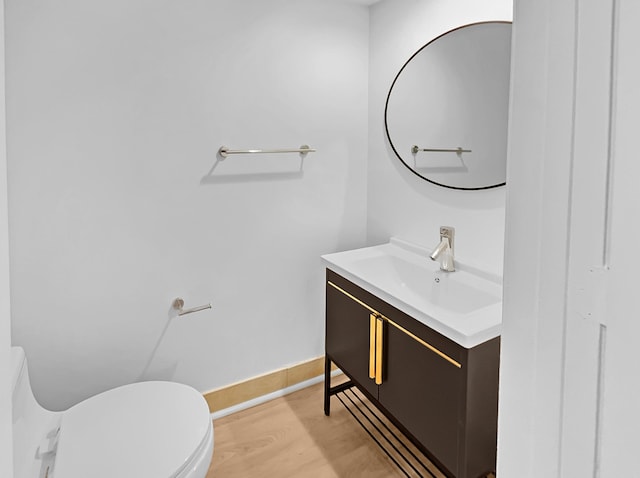 bathroom with hardwood / wood-style flooring, toilet, and vanity