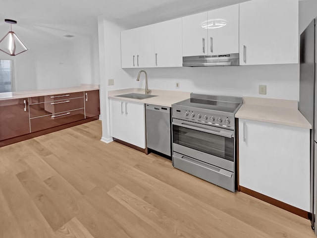 kitchen with appliances with stainless steel finishes, sink, light hardwood / wood-style flooring, white cabinetry, and hanging light fixtures