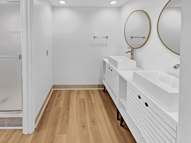 bathroom with a shower with door, hardwood / wood-style floors, and vanity