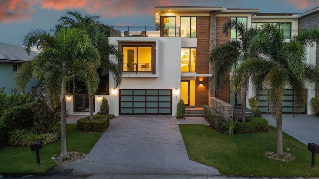 view of front of property featuring a garage, a yard, and a balcony