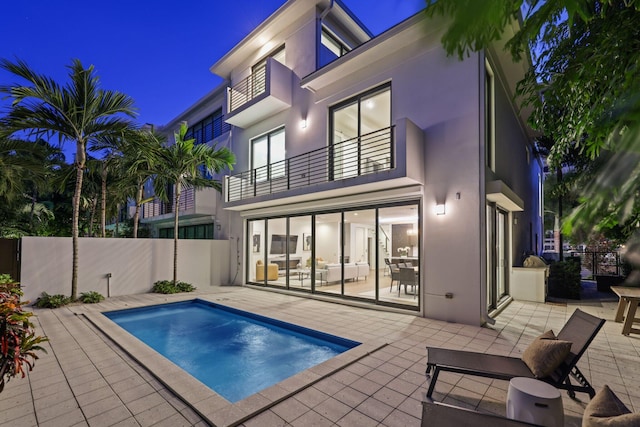 pool at night featuring a patio