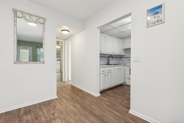 kitchen featuring sink, hardwood / wood-style flooring, white electric stove, tasteful backsplash, and white cabinetry