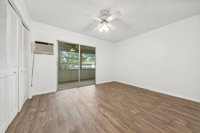 unfurnished bedroom with ceiling fan, hardwood / wood-style floors, and an AC wall unit