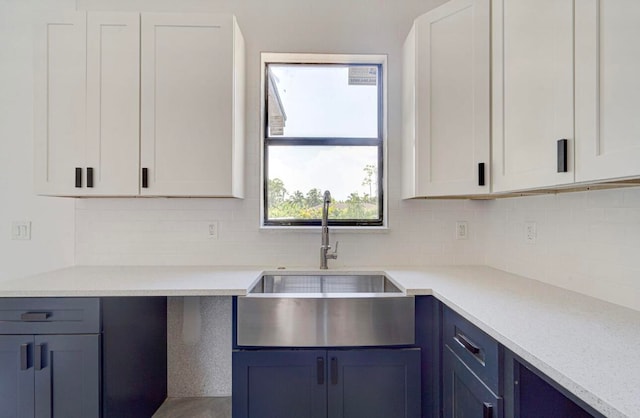 kitchen with white cabinets, decorative backsplash, sink, and light stone countertops