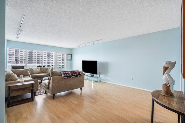 living room featuring light hardwood / wood-style flooring, a textured ceiling, and track lighting